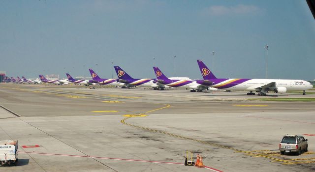 BOEING 777-300 (HS-TKE) - Thai Airways 777-3D7 HS-TKE leading a lineup of twelve with her A330, A300, 747, and 777 sisters at Bangkok (BKK) on Oct 14, 2014.