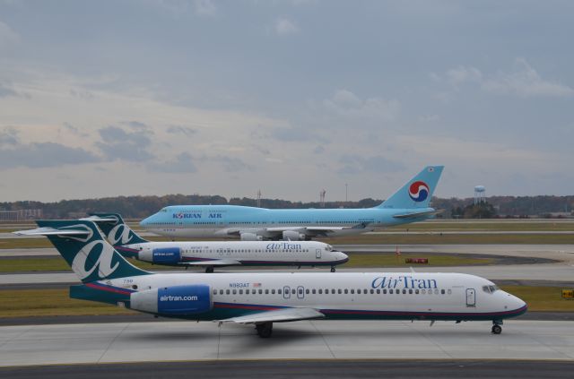 Boeing 747-200 (HL7490) - Coming and going!  KAL Whale starts his roll down Runway 9L while two AirTrans wait in line.  This was the last good photo I got before a nice Atlanta Police officer chased me off the parking garage.