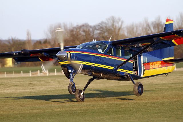 G-OHPC — - [cn.20800224]. Cessna 208 caravan G-OHPC action landing on the muddy grass strip after delivering Skydivers to their drop at Lashenden EGKH Headcorn Aerodrome Kent UK 19.2.2012.