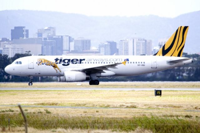 Airbus A320 (VH-VNG) - Heading for Terminal 1 after landing on runway 23, on the last day of the Australian summer. Thursday 28th February 2013. The Adelaide city skyline can be seen in the gloomy background.