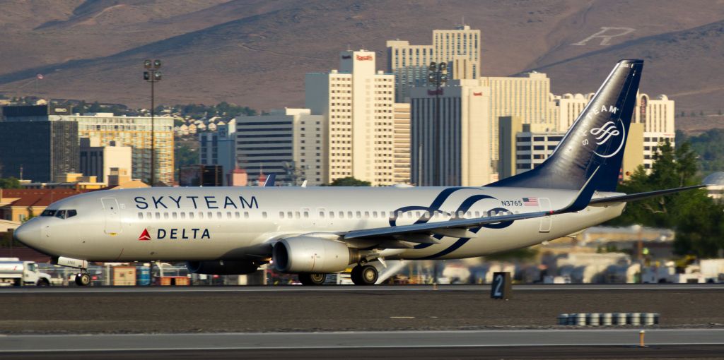 Boeing 737-800 (N3765) - The first rays of sun cast a golden hue on downtown Reno and on Deltas N3765, a B738 dressed in Skyteam garb, as it rolls down runway 16R to end its overnight visit to RNO.