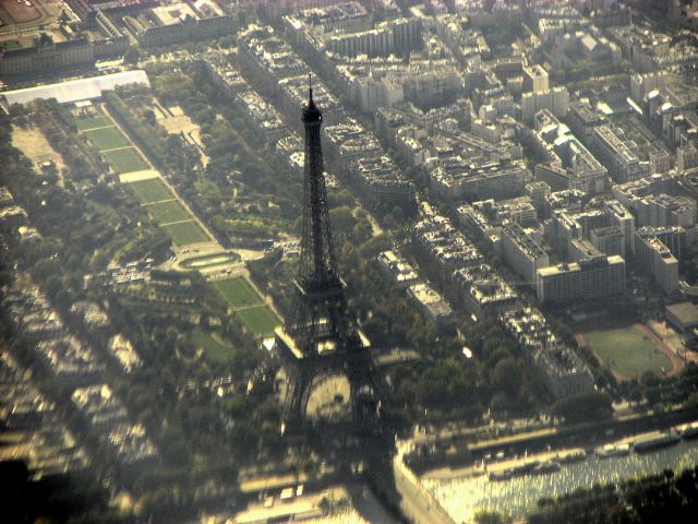 — — - On our flight back home from Istanbul via Paris we flew over over the Eiffel Tower.  Unfortunately I had the sun on my window, so there is this bluish haze, and as it was close to the lower edge of the window there is a lot of distortion.
