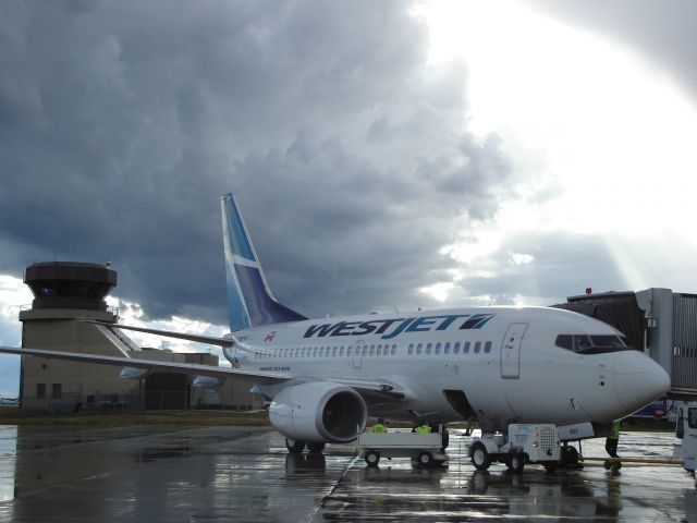 BOEING 737-600 (C-GWSK) - WestJet Boeing 737-600 at the loading bridge at the Fort McMurray Alberta Airport on July 25th, 2007. The storm brewing to the west in the picture developed into a hailstorm with golfball sized stones that caused significant damage to homes just west of the airport.