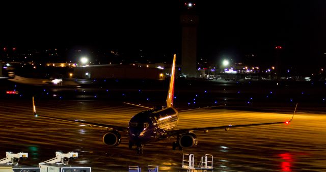 Boeing 737-700 (N421LV) - Southwests N421LV glows gold under the ramp lighting as it turns into its gate position at KRNOs Terminal B.  In the background (left), Horizons N431QX is into its deceleration roll after landing on runway 16R.