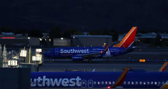 Boeing 737-700 (N954WN) - Southwest's newest special livery, the WALT DISNEY WORLD 50 YEARS paint scheme, is still visible as N954WN taxies away from the terminal in the very final few moments of dark dusk light for a 6:55 PM departure to San Jose (KSJC).