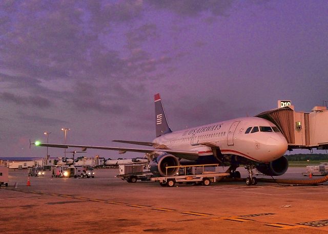 Airbus A319 (N725UW) - Sunset at gate D-10, Charlotte, North Carolina, bag crews are just moving into position to load the aircraft. Shot with Sprint HTC EVO 4 cellphone, manual settings