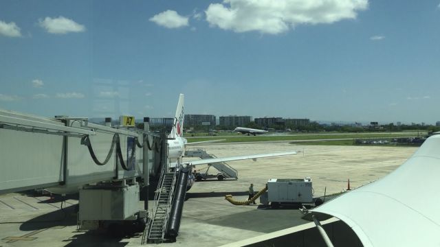 Airbus A320 (N586JB) - JetBlue plane parked at gate A7 in San Juan. Meanwhile a US Airways jet lands on runway 10.