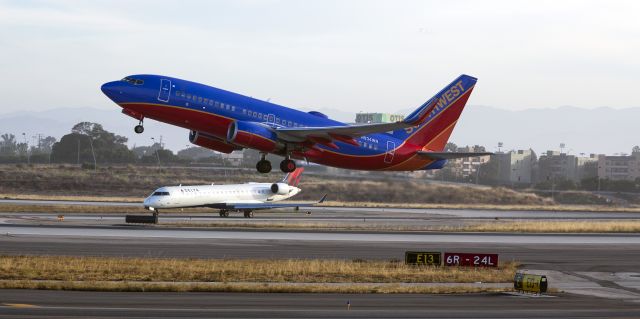 Boeing 737-700 (N934WN) - This Southwest 737 is leaving Los Angles (LAX) as the Delta Connection regional jet waits patiently after landing on the adjacent runway.
