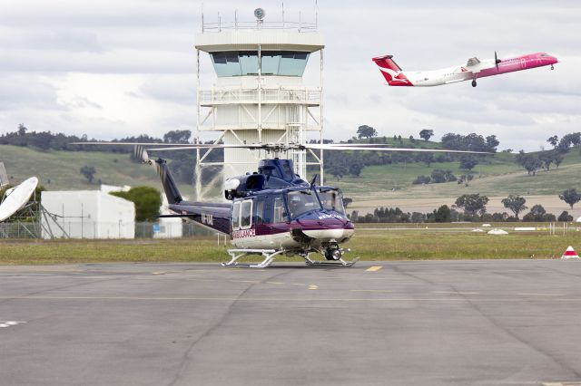 Bell 412 (VH-VAU) - Australian Helicopters (VH-VAU) Bell 412EP, with QantasLink (VH-QOH) Bombardier DHC-8-402Q taking off, at Wagga Wagga Airport.