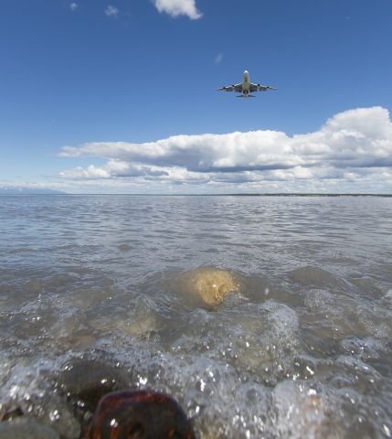 — — - 6-19-14 A UPS 747 was about to land at Anchorage International Airport. With my wide angle lens, I made the small stones in the inlet seem large and the plane small.