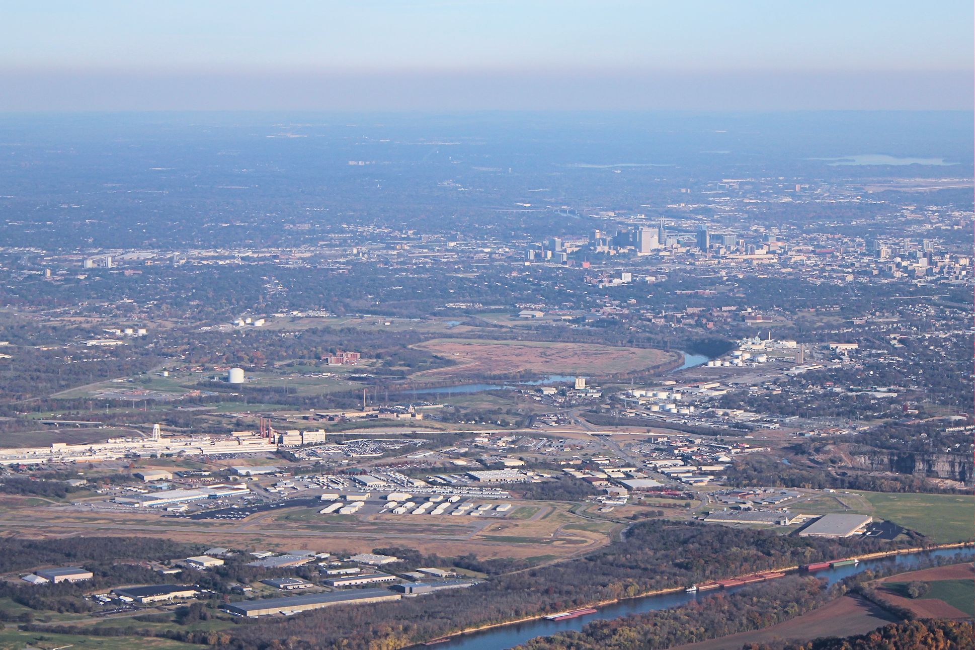 — — - John C. Tune Airport (foreground, lower left), the Cumberland River, and the Nashville skyline.