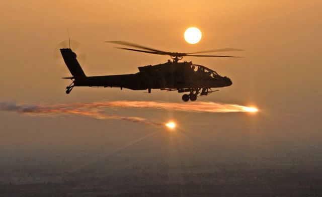 — — - An Ah-64 military helicopter firing.