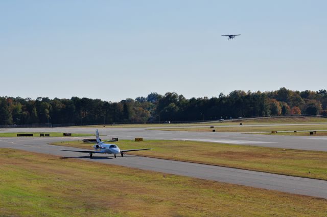 — — - A Citation Bravo taxis to the FBO as a Fairchild overflys runway 6 at Hickory Regional Airport