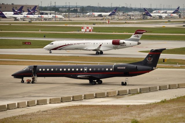 Embraer ERJ-145 (N500DE) - Joe Gibbs racing team aircraft N520JG taxiing in background.