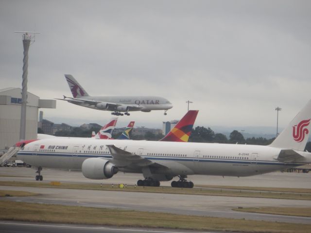 BOEING 777-300ER (B-2046) - An Air China 777-39L(ER), registration B-2046 rolls down a Heathrow taxiway, with a Qatar A380 on final approach in the background.