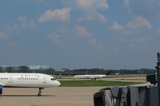 Boeing 757-200 (N704X) - 082512 Delta B757 taxiing in, Delta MD88 N988DL taxiing out to Rwy28R, and in the distance United Dash8 on 28R