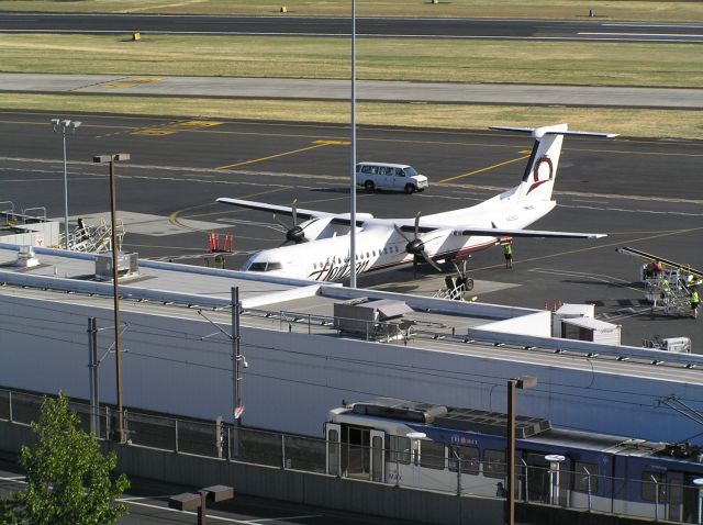 de Havilland Dash 8-400 (N4260X) - On the parking deck at PDX toward 25L-7R; note Tri-Met MAX light-rail car in foreground, serving PDX from downtown on the Red Line. 2009-07-02, around midday.