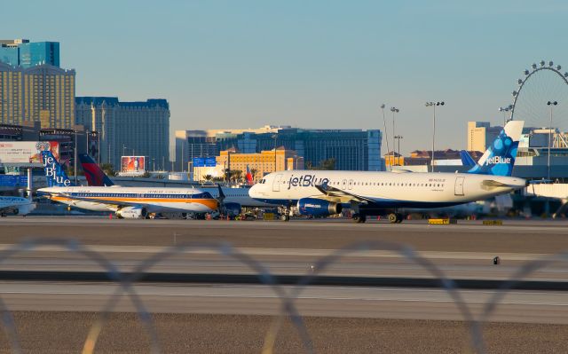 Airbus A320 (N763JB) - As N763JB taxis for departure, another JetBlue flight is in the middle of its takeoff run.