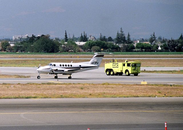 Beechcraft Super King Air 200 (N117PA) - KSJC - Engine 20B of the San Jose International Airport Fire Dept follows N117PA after an emergency landing with gear indicator problems - but obviously no issues as this twins taxis to ACM. Date early 1990s.