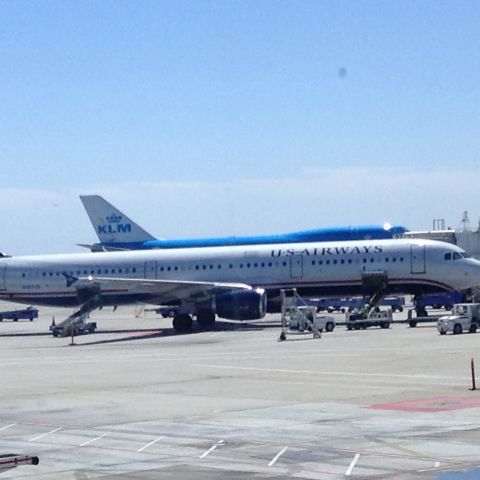 Airbus A321 — - A321 sits at the gate at SFO while a KLM 747 is taxiing to the gate behind the terminal im in