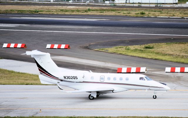 Embraer Phenom 300 (N302QS) - N302QS taxing to parking on the cargo ramp with the closed Bravo taxi way in the back ground.