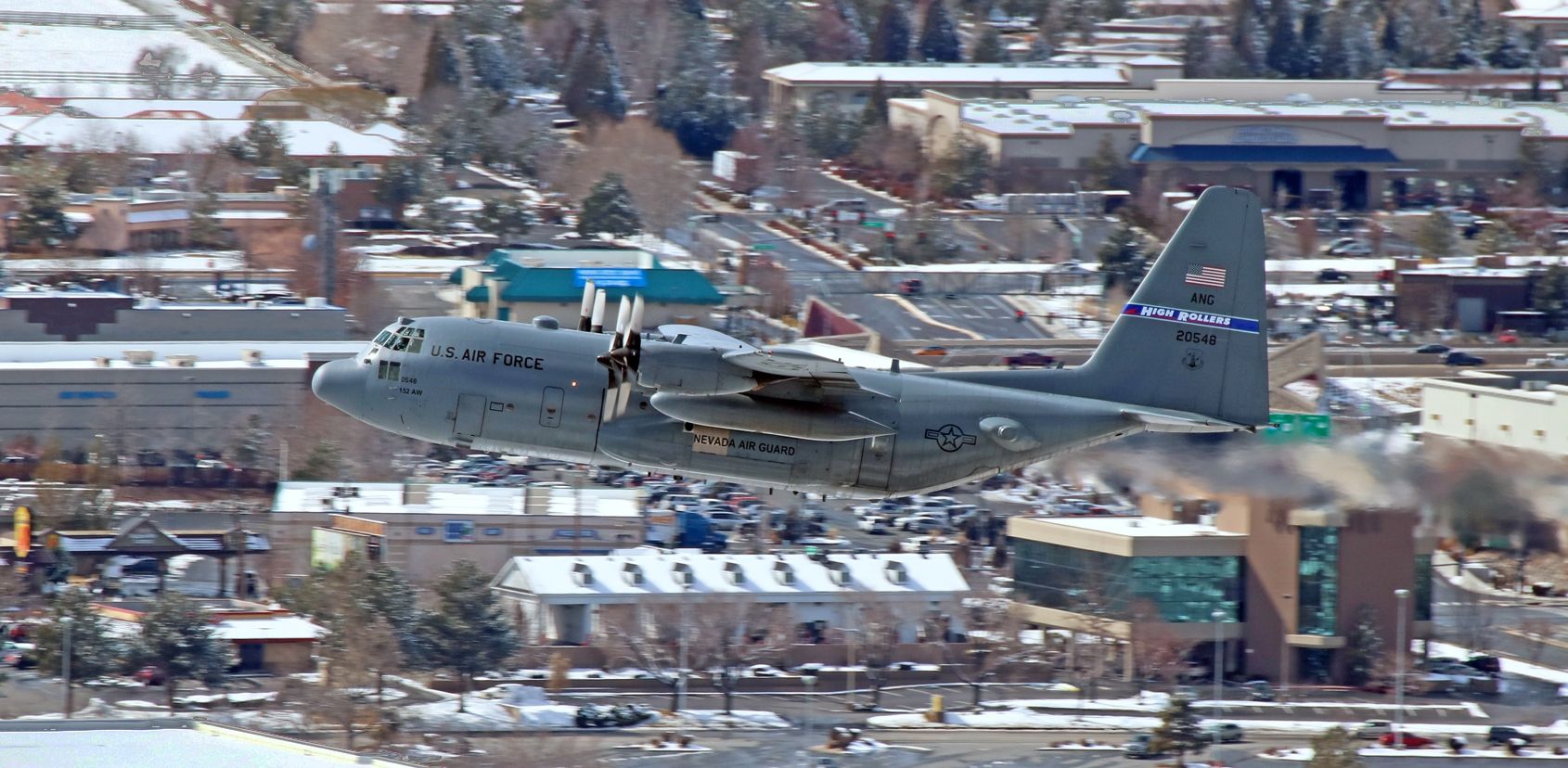 Lockheed C-130 Hercules (92-0548) - The first C-130H Hercules (92-0548) to go airborne during yesterdays NevANG "High Rollers" exercise propclaws its way directly past my spotting location as it climbs out from Reno Tahoe Internationals 16R. This click shows how difficult it is to spot a military metalbird; look at how well it blends into the shopping mall area behind it ... and it was not very far away from me when it went past. br /br /* Although the FA data counter below this photo indicates that this is the first photo of 92-0548 to be posted into the gallery, this is actually the second pic. A few months ago, I posted a snap (also taken at RNO) of an N3N-3 (N4009A) and in the background of that pic this same Herc was arriving with Santa aboard. *br /br /Prior to being here as part of the 152nd AW "High Rollers," this Hercules was assigned to "The Rock."