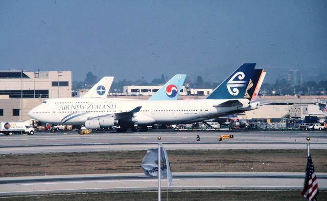 Boeing 747-400 (ZK-NBS) - KLAX - Imperial Hill View again this time another dusty slide converted to digital Air New Zealand 747-4 - CN:24386 LN:756 arriving at the gate in this January 1999 photo. Note there are 5 747s in this photo, a scene well never see again at LAX. The VARIG most likely is a 747-3 as I saw this at LAX frequently. This jet delv new to ANZ and leased to Cathay Pacific for a few years before being returned to ANZ in 1991.This jet now scrapped.