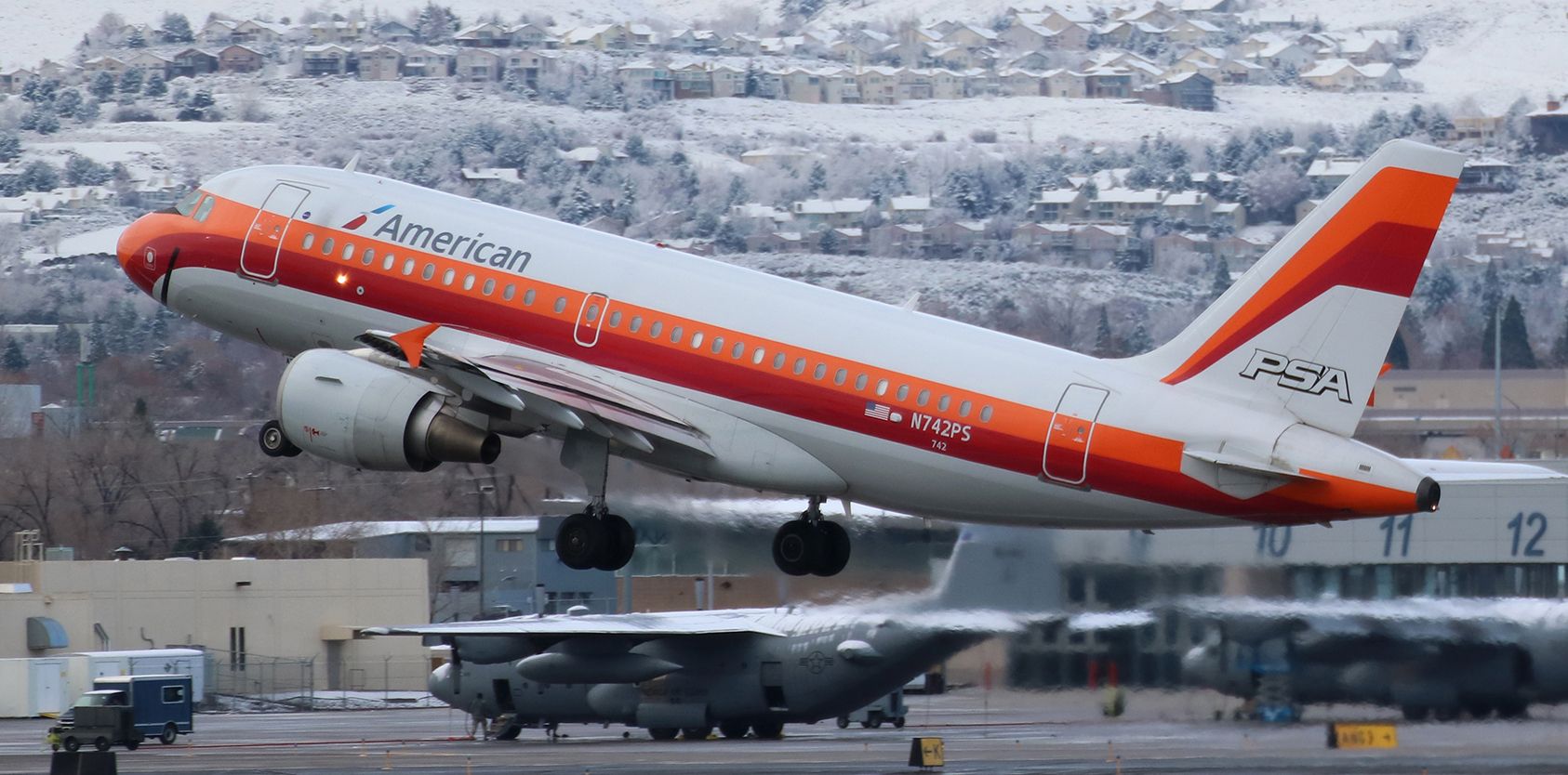 Airbus A319 (N742PS) - The first appreciable amount of snow in the Truckee Meadows in well over two years created a nice white backdrop to this capture of Americans N742PS, the colorful PSA heritage liverybird, clicked here climbing away from Reno Tahoe Internationals runway 16R.