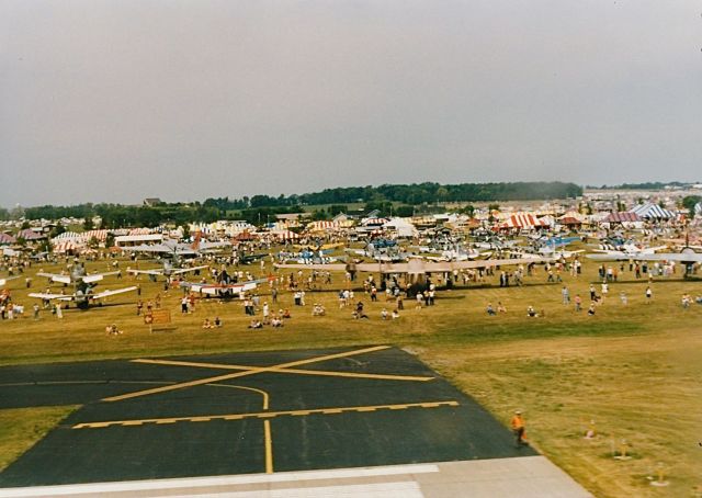 — — - War Bird parking west of the end of runway 18 at an EAA Fly In and Air Show