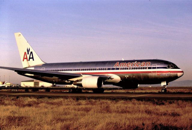 BOEING 767-200 (N305AA) - KSFO apprx date early 1990s. this American 767-2 on slow taxi to Runway 1R for departure. The dirt parking lots here at SFO were great for late PM sun angle photos view looking east. - Smaller jets were better to film as the heavies were so big one needed a good wide-angle lens. This probably headed to ORD or JFK.