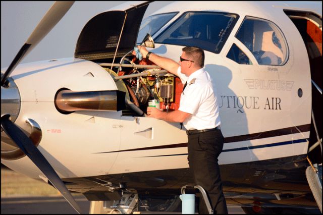 Pilatus PC-12 (N451SS) - The pilot topping off the oil level of the PC-12