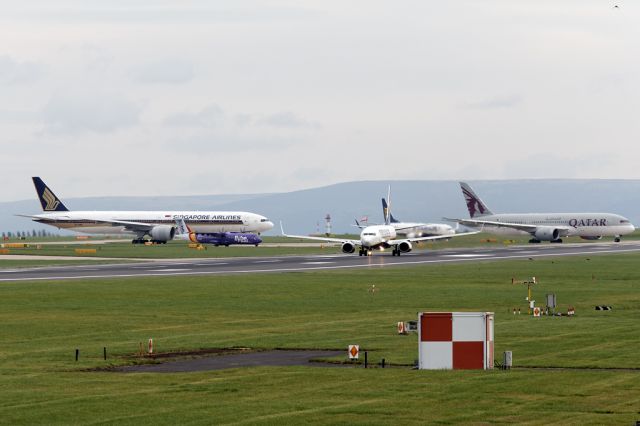 Boeing 737-800 (EI-EKV) - RYR3212 departs to Girona as a couple of heavies wait in the background, 9V-SWK and A7-BCA