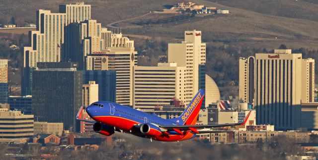 Boeing 737-700 (N256WN) - Sunrise snap catches Southwests N256WN when it climbs into my viewfinder while passing between me and the downtown Reno skyline at 7:10 AM to begin its new workday with an early morning trip to Las Vegas.