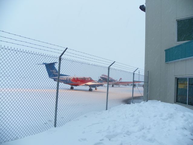 — — - Polar 5 in the background with a Life Guard King Air 200 in the foreground with heavy snow coming down.