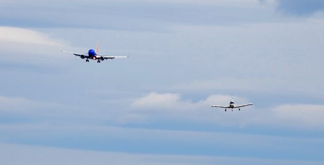 Piper Cherokee (N7824W) - The Reno Air Races are back? Well, not quite. This is indeed an "air race" and it is taking place in Reno, but ....br /What is seen here is a Southwest B737 (N7712G) on short final to RNO's Runway 16R as a Piper Cherokee (N7824W) makes its s/final to RNO's parallel Runway 16L. Although the heat distortion shows that both aircraft are still a bit out from their respective runways, the Southwest is actually much farther away and only appears to be as close as the Cherokee because it (the B737) is bigger. The Piper touched down first so I suppose that in the loosest sense it "won" this race.