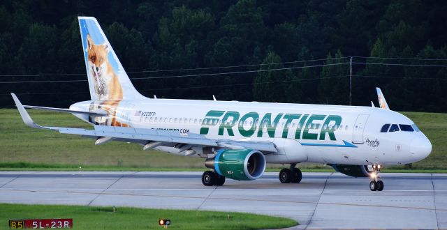 Airbus A320 (N229FR) - Peachy the Fox making the turnoff from 5L under an evening rain cloud, arriving from TTN, I believe.  Peachy needs to get a touch-up, poor thing.  From the RDU observation deck, 9/3/18.