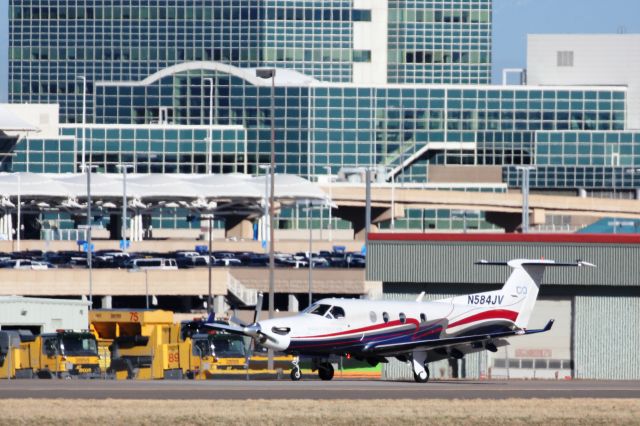 Pilatus PC-12 (N584JV) - On taxiway M with airport office building in background.