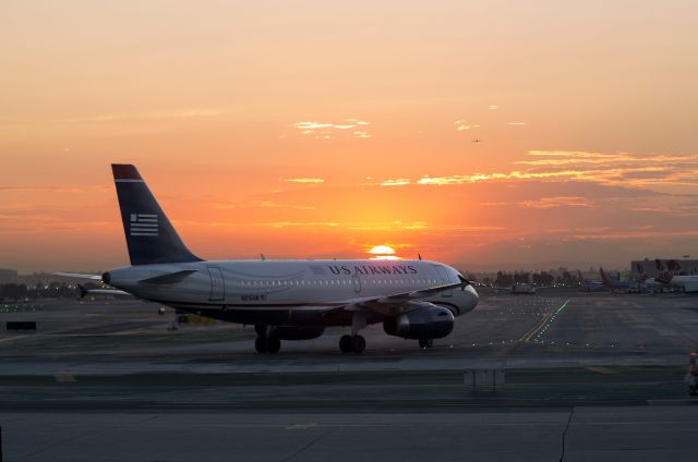 Airbus A319 (N815AW) - Early morning taxi at LAX (Los Angeles, California USA); This US Airways Airbus A319 is being taxied from the hangar to the gates by Aircraft Maintenance Technicians after a routine maintenance check. A Qantas 747 is on final approach in the distance.