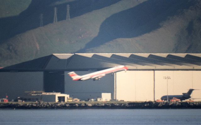 McDonnell Douglas MD-80 — - KSFO- long distance 1000mm shot of PSA MD-80 departing the 1L/R runways at San Francisco for San Diego, in 1988- note the AA 727 at the SFO maintenence base in the northerly view photo taken with a Minolta XD-11 and Celestron C-90 ( 1000mm )