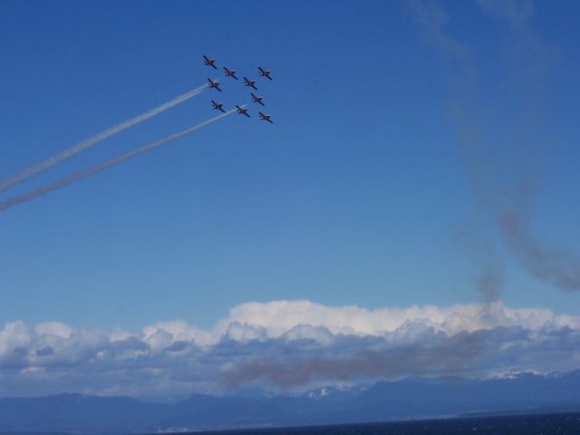 — — - Canadian Snow Birds practice  "Silver Dart" formation  over CFB Comox on the shores   of the Sailish Sea