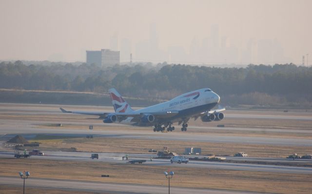 Boeing 747-400 (G-BYGB) - BAW196 heavy lifting off of 33R with downtown Houston in the background.