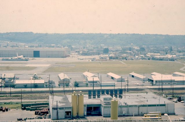 BOEING 747-100 (N7470) - KBFI - Summer 1975 - photo taken by me from where about our house used to be before Interstate 5 was built( our house was demolished by the State of Washington) Summer 1964. This view looking west at the north end of BFI. If you can see where the taxi way is east of the main runway, and how narrow it is, we used to see Boeing B-52 Tall tails" taxi on this side of the runway from the left, sometime 4-5 lined up and other B-52s from the west side of the runway, and all of them would take off back to back to back, smoking like crazy and just layer the area in back smoke, and it was loud as all heck,,,,,but so cool. When the B-52s would return, they always used the drag chute out the back and many had them deployed on final over south Seattle, on over Georgetown district and onto the runway. The B-47s were even better pre-1964. The building in the foreground is Krusteazs Pancake Company where they made the pancake mix. My 4 brothers and I would always be down there walking the tracks and goofing around in the railroad box cars.