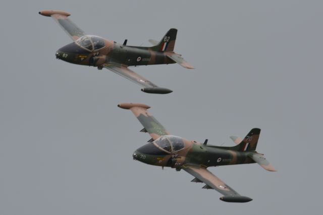 MULTIPLE — - BAC Strikemasters ZK-NTY (upper) and ZK-STR opening the first flying session at the NZ Warbirds Open Day on 22 November 2015. Conditions were overcast, just after a rain shower, with a strong blustery wind.