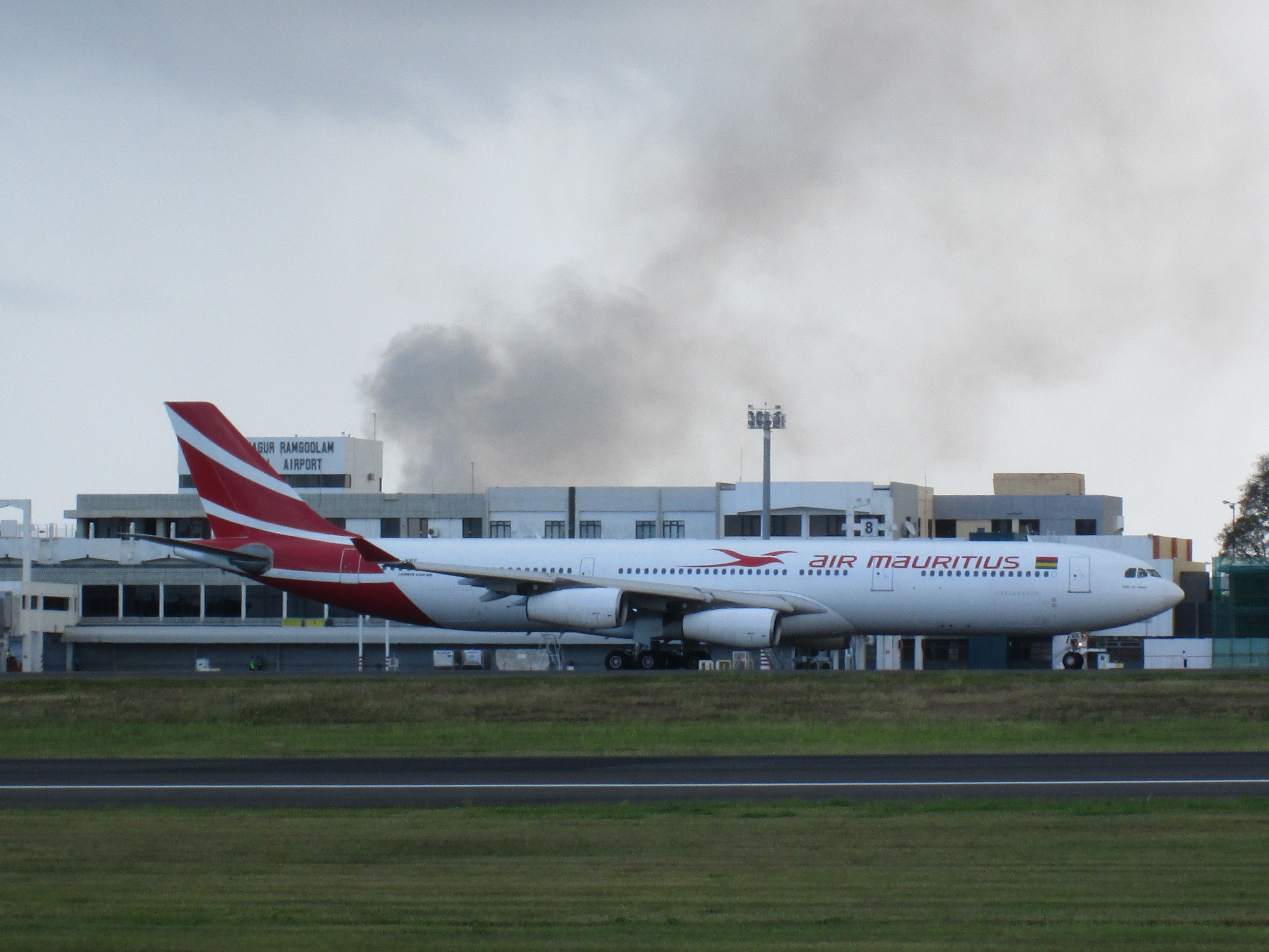 Airbus A340-300 (3B-NBE) - Cane Field on fire behind airport.