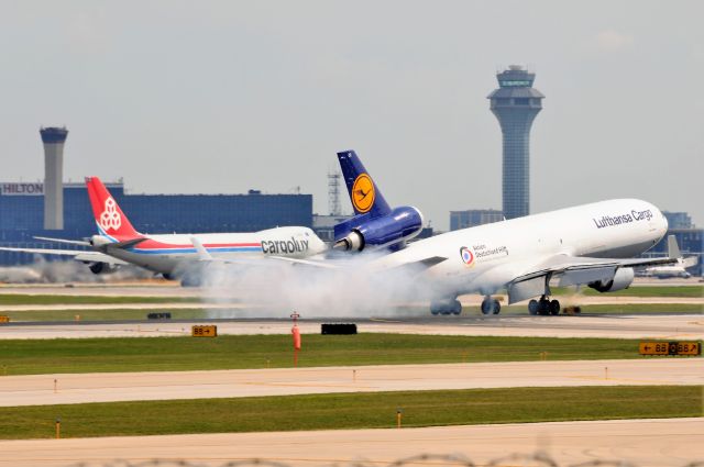 Boeing MD-11 (D-ALCC) - SMOKING THE MAINS. CLX LX-VCC departing in the background.