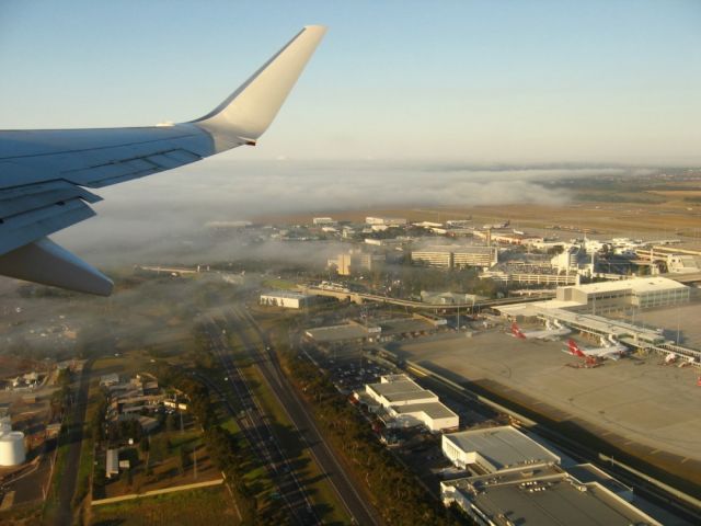 Boeing 737-700 — - Early morning departing from Melbourne Airport, with fog clearing in the background.