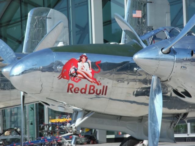 Lockheed P-38 Lightning (N25Y) - This photo was taken outside of Hangar 7 (Glass Hangar) at Mozart Airport and I noticed a change to the nose art on N25Y.  As seen in the photo, the nose art now features a "lady on the Red Bull".  No other changes were visible on the exterior.