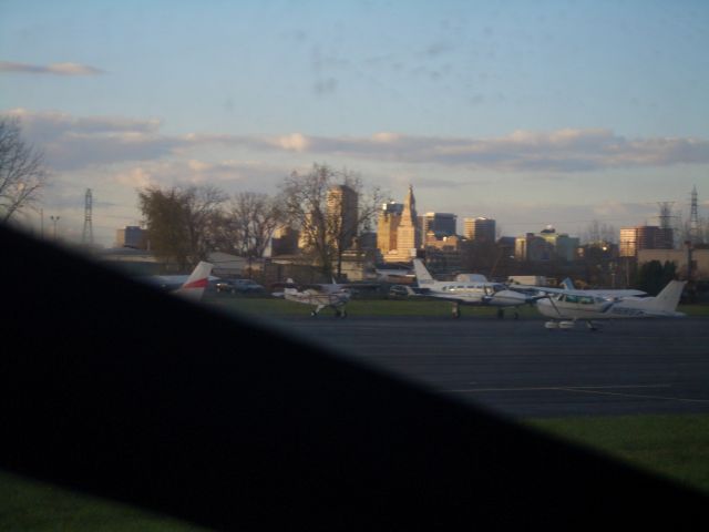 — — - Brainard Airport from taxiway Alpha looking out to the city skyline at sunset.