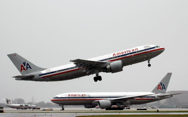 Airbus A300F4-600 (N70074) - Taking off on R 26L in a light rain while a company B-777 taxis east on N after landing.