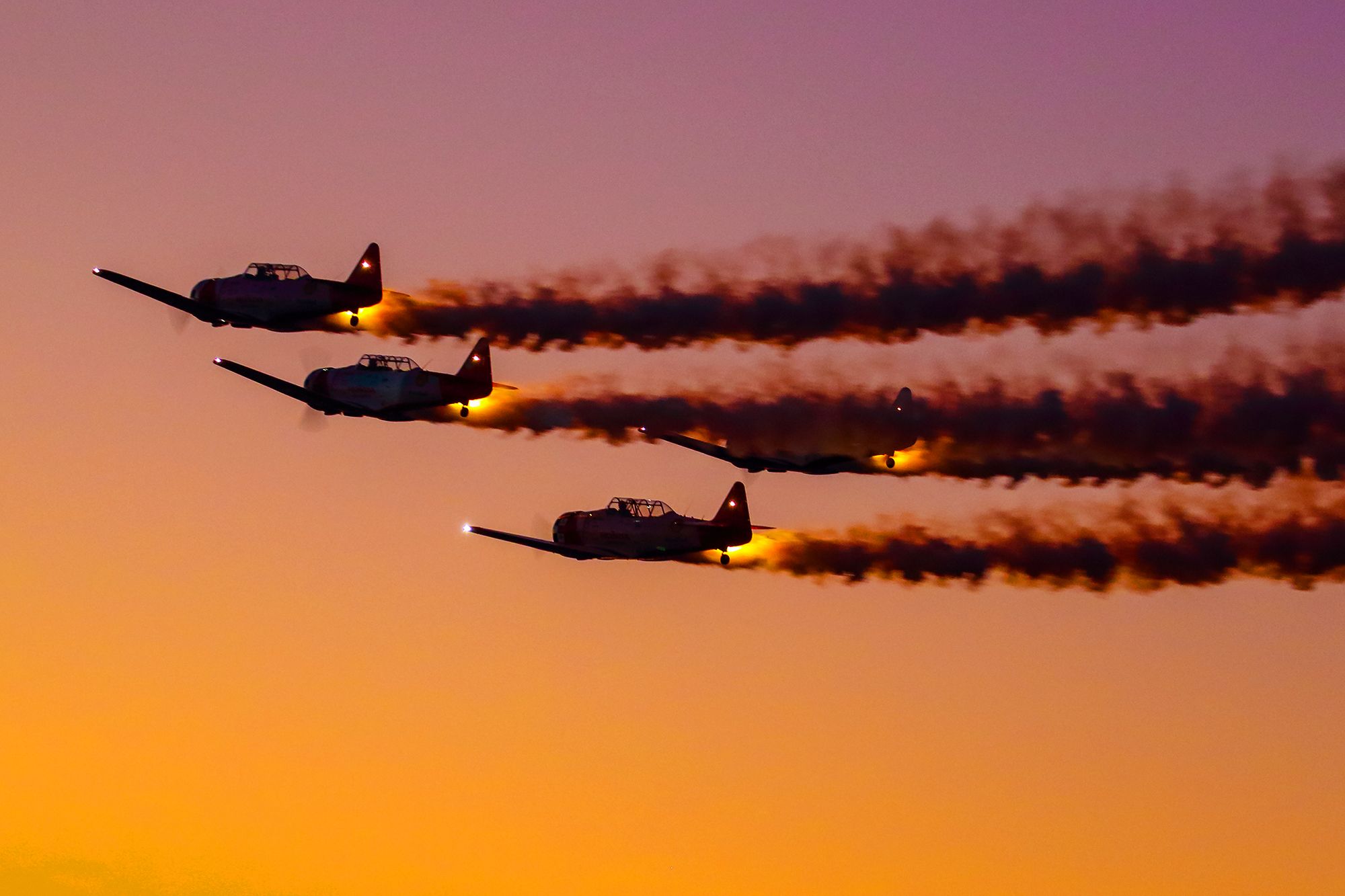 — — - The Aeroshell flight team was performing at dusk to kick off the nighttime aerial performances at the 2022 Sun N Fun airshow. The AT-6 Texans with their smoke engaged and brilliant aircraft lights combined with the evening sky came together perfectly to create a beautiful image. I shot this with my Canon 100-400mm IS II lens at the focal length of 135mm. Camera settings were 1/200 shutter, F5, ISO 1600. Please check out my other aviation photography. Votes and positive comments are always appreciated. Questions about this photo can be sent to Info@FlewShots.com